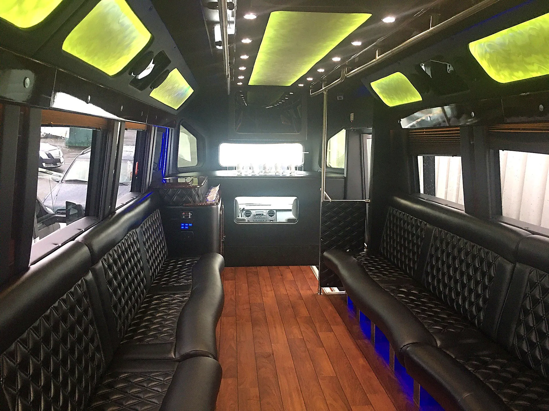 Empty bus interior with dark bench seating and yellow-green ceiling lights