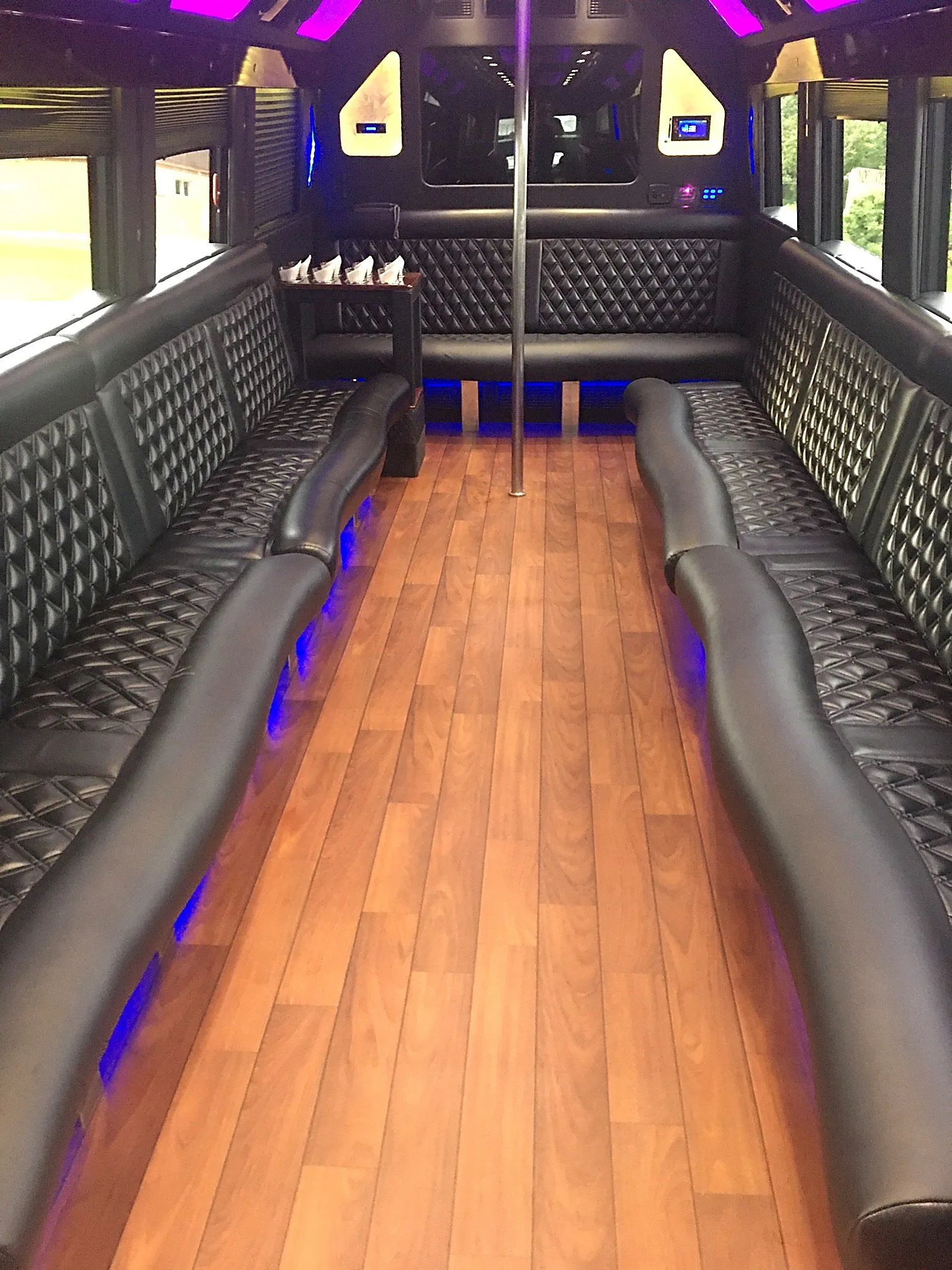 Bus interior with wood flooring, dark seating and purple lighting