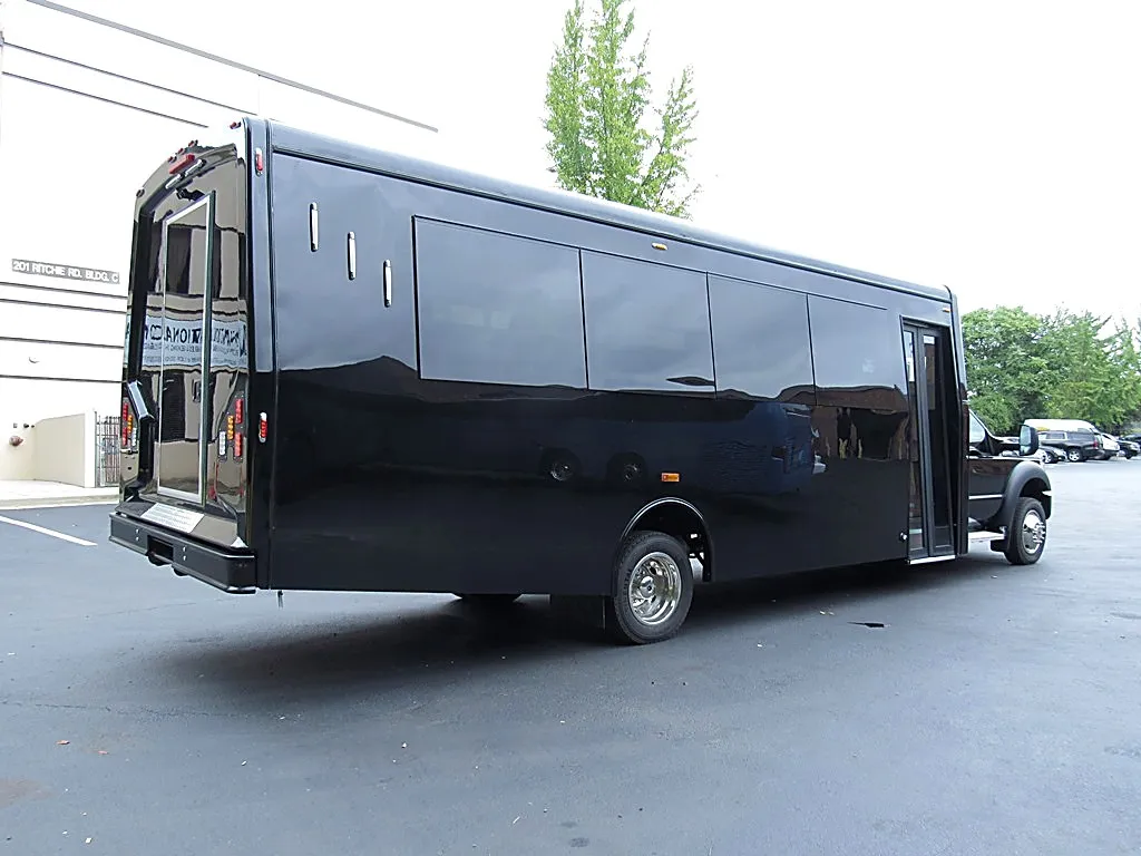 Rear and side view of a black bus parked outdoors in daylight