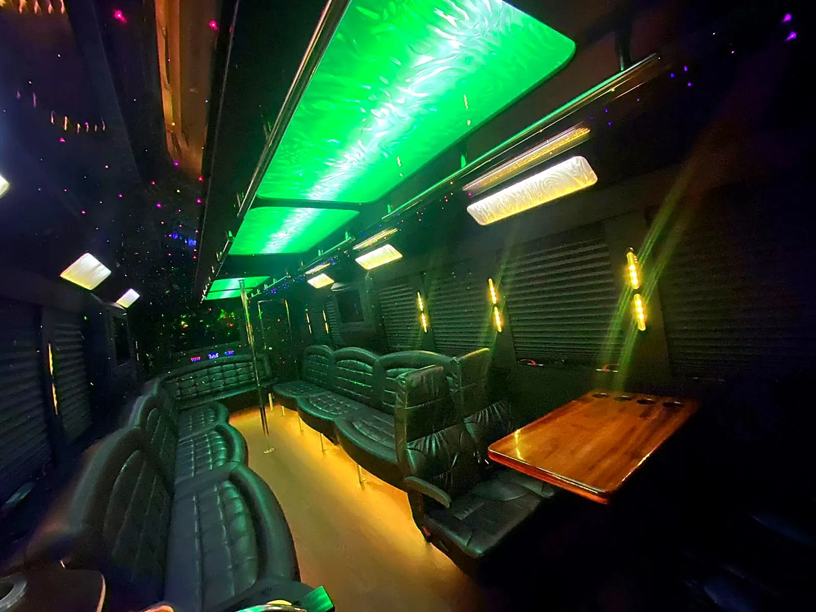Bus interior with green ceiling lighting and a small table